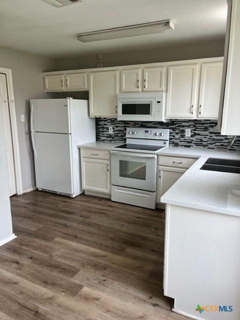 kitchen featuring tasteful backsplash, light countertops, a sink, white cabinets, and white appliances