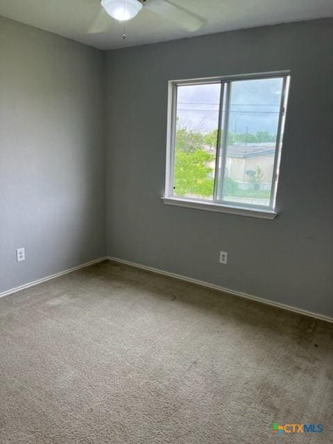 carpeted spare room with baseboards and a ceiling fan