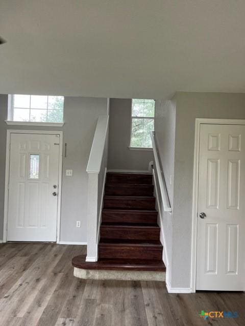 foyer with stairway, baseboards, wood finished floors, and a wealth of natural light