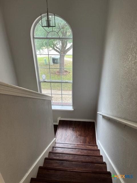 staircase with a textured wall and a healthy amount of sunlight