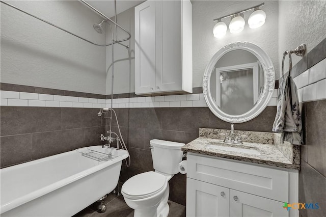 bathroom with vanity, toilet, a tub to relax in, and tile walls