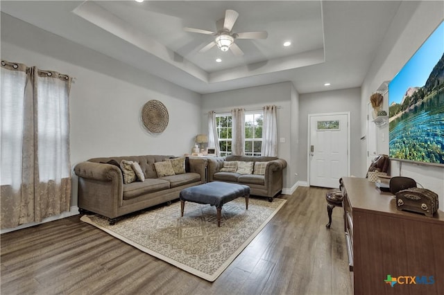 living room with a tray ceiling, ceiling fan, and hardwood / wood-style flooring