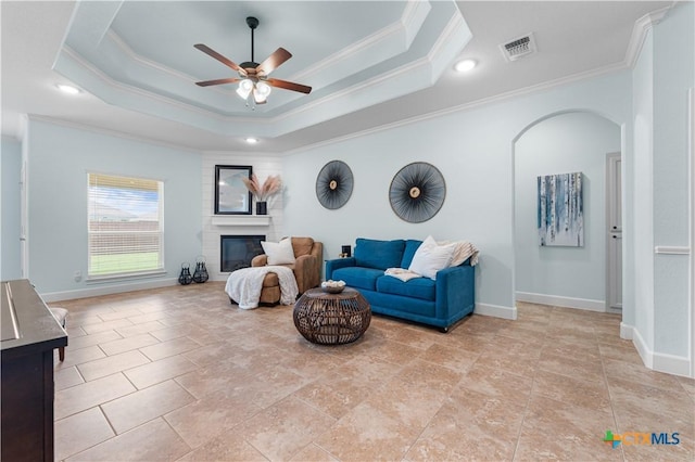 2655 Belle Hubbard Trl, Belton, TX 76513 - living room with crown molding, a ceiling fan, a fireplace, arched walkways, and a tray ceiling