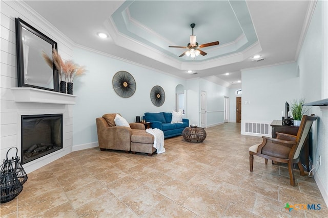2655 Belle Hubbard Trl, Belton, TX 76513 - living area featuring crown molding, ceiling fan, a large fireplace, stone finish flooring, and a tray ceiling