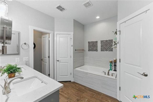 full bath with visible vents, a sink, a bath, and double vanity