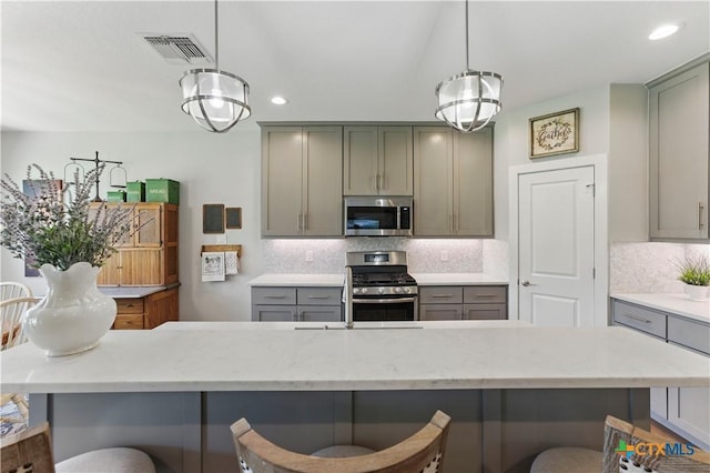 kitchen with recessed lighting, appliances with stainless steel finishes, a breakfast bar area, and gray cabinetry