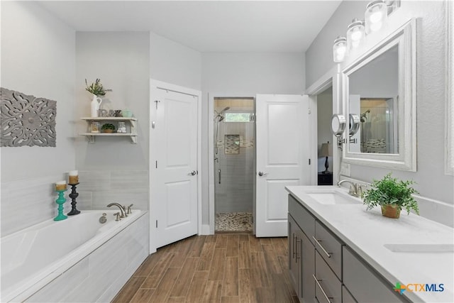 full bathroom featuring wood finished floors, a sink, a bath, and a stall shower