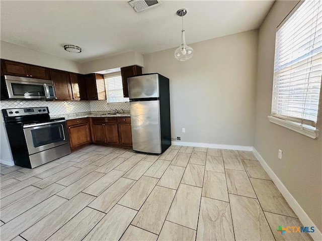 kitchen with tasteful backsplash, stainless steel appliances, hanging light fixtures, and sink