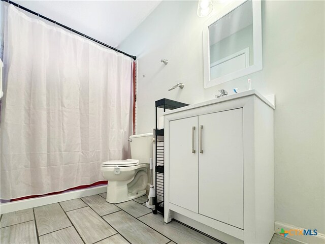 bathroom with toilet, vanity, and walk in shower