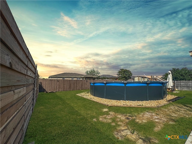 yard at dusk featuring a fenced in pool