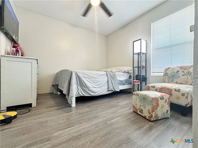 bedroom featuring hardwood / wood-style floors, ceiling fan, and a textured ceiling