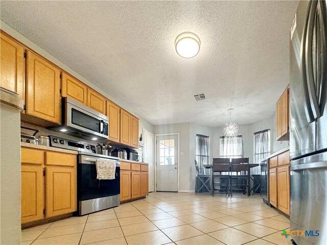 kitchen featuring hanging light fixtures, a textured ceiling, and appliances with stainless steel finishes