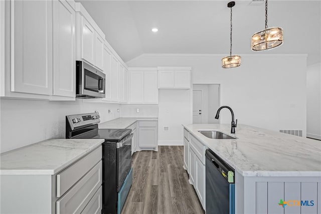 kitchen with stainless steel appliances, pendant lighting, vaulted ceiling, a center island with sink, and white cabinets