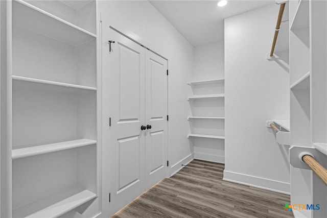 walk in closet with dark hardwood / wood-style floors