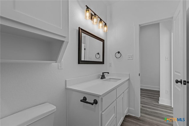 bathroom with hardwood / wood-style floors, vanity, and toilet