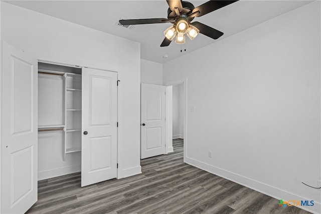 unfurnished bedroom with ceiling fan, dark wood-type flooring, and a closet