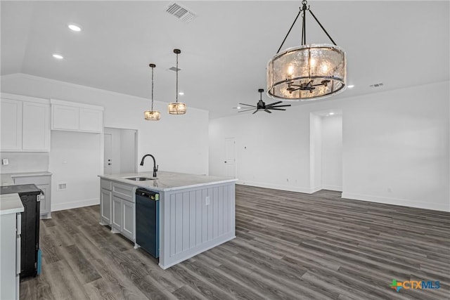 kitchen with dark wood-type flooring, a center island with sink, ceiling fan with notable chandelier, white cabinets, and hanging light fixtures