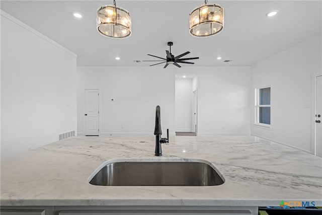 kitchen featuring light stone counters, sink, and pendant lighting