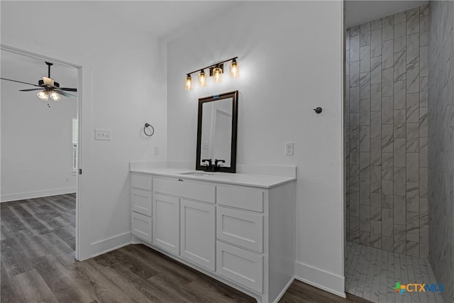 bathroom featuring a tile shower, ceiling fan, hardwood / wood-style floors, and vanity