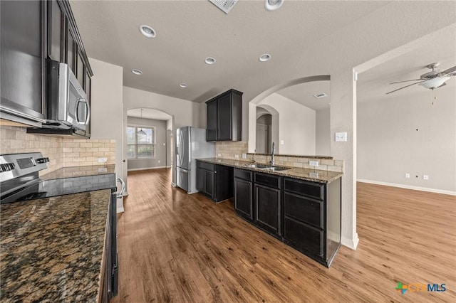 4703 Prewitt Ranch Rd, Killeen, TX 76549 - kitchen featuring stainless steel appliances, a sink, wood finished floors, arched walkways, and tasteful backsplash
