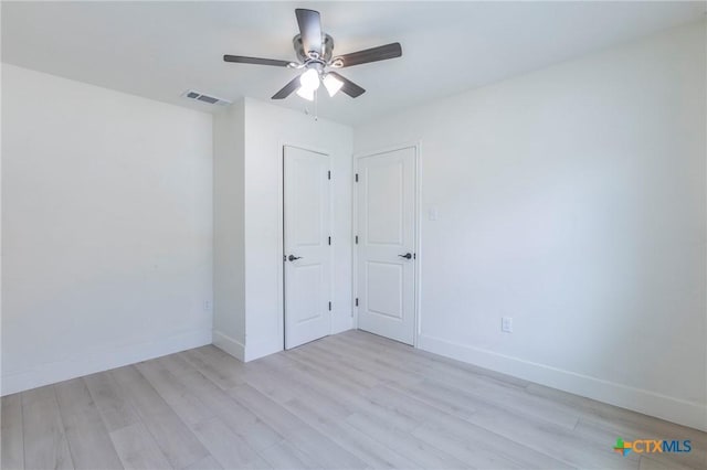 unfurnished bedroom featuring light wood-style flooring, visible vents, ceiling fan, and baseboards