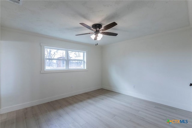 empty room featuring ornamental molding, ceiling fan, light wood finished floors, and baseboards