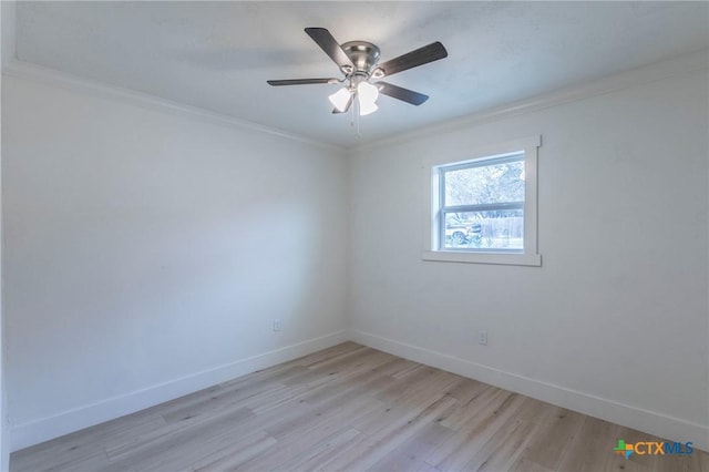 spare room with ornamental molding, light wood-style floors, and baseboards