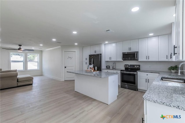 kitchen featuring decorative backsplash, open floor plan, a center island, stainless steel appliances, and a sink