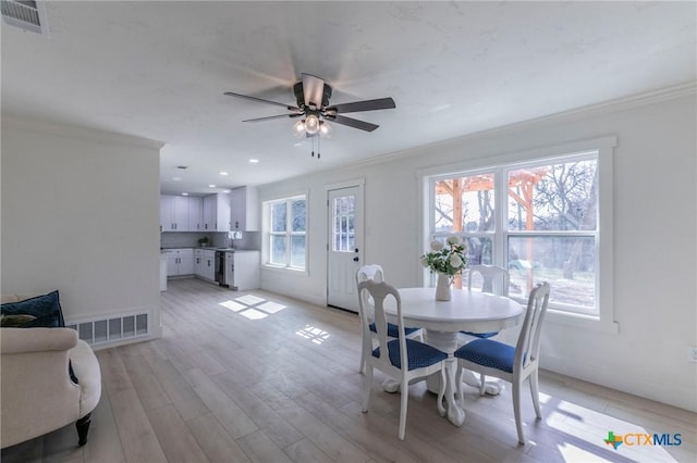 dining space featuring visible vents, crown molding, and light wood finished floors