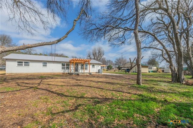 rear view of property featuring a yard and a pergola