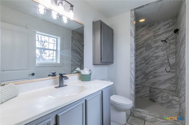 bathroom featuring tiled shower, vanity, and toilet