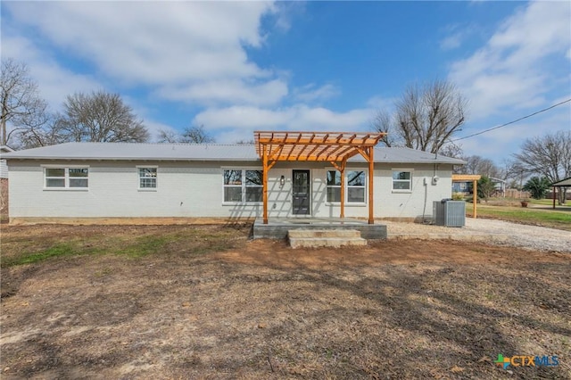 back of house with central AC unit, a pergola, and brick siding