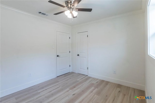 empty room with light wood-type flooring, baseboards, visible vents, and ornamental molding