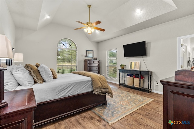 bedroom with hardwood / wood-style flooring, ceiling fan, multiple windows, and vaulted ceiling