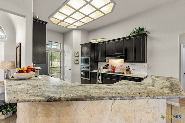 kitchen with stainless steel appliances, light stone counters, decorative backsplash, and kitchen peninsula