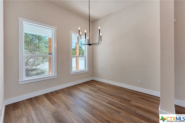 unfurnished dining area with hardwood / wood-style flooring and a chandelier