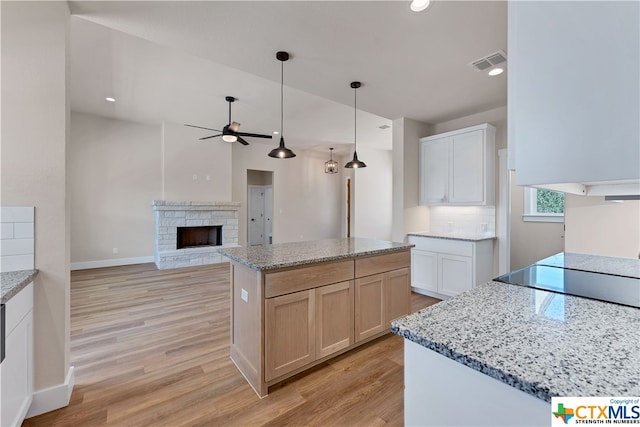 kitchen featuring white cabinets, light wood-type flooring, a fireplace, and a kitchen island