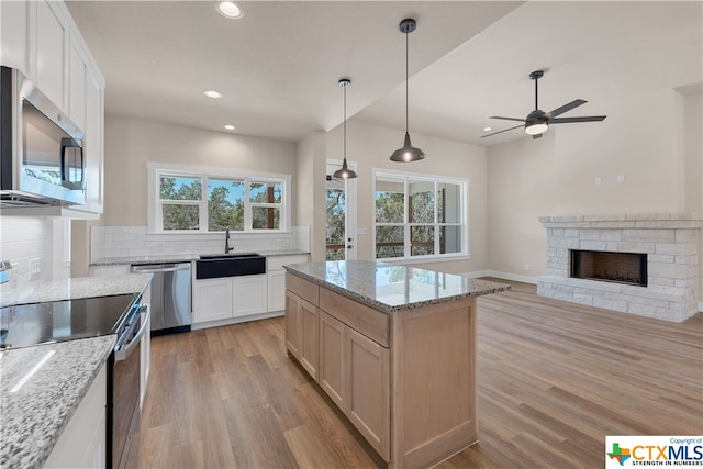 kitchen featuring light stone countertops, white cabinetry, appliances with stainless steel finishes, and a center island