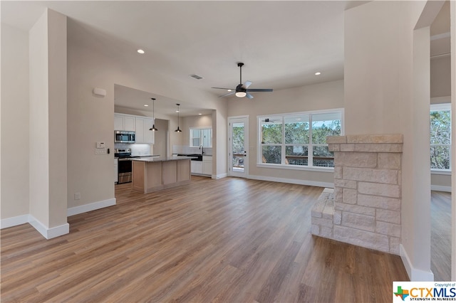 unfurnished living room featuring ceiling fan, plenty of natural light, and light wood-type flooring