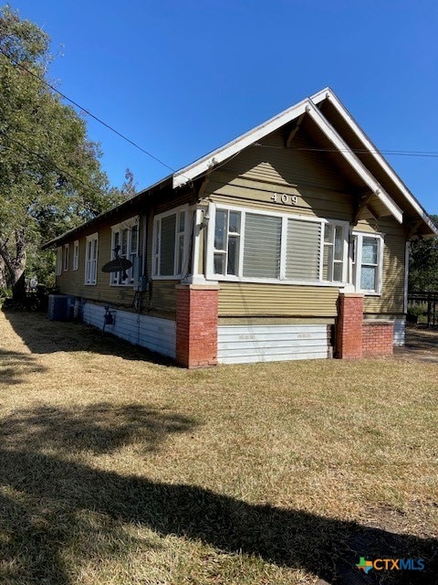 view of side of property with a yard and central AC