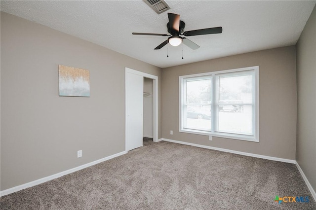 unfurnished bedroom featuring visible vents, a textured ceiling, a closet, carpet flooring, and baseboards