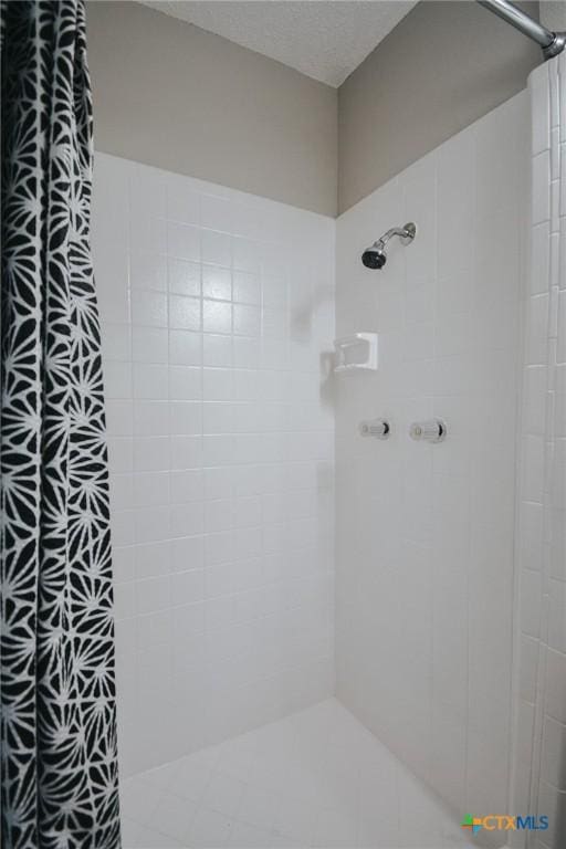 bathroom featuring tiled shower and a textured ceiling