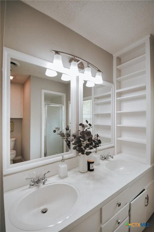 full bathroom with a sink, toilet, a shower stall, and a textured ceiling