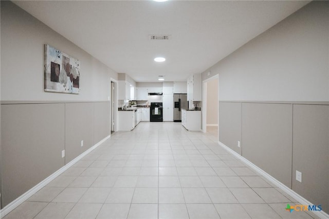 corridor with visible vents, wainscoting, and a decorative wall