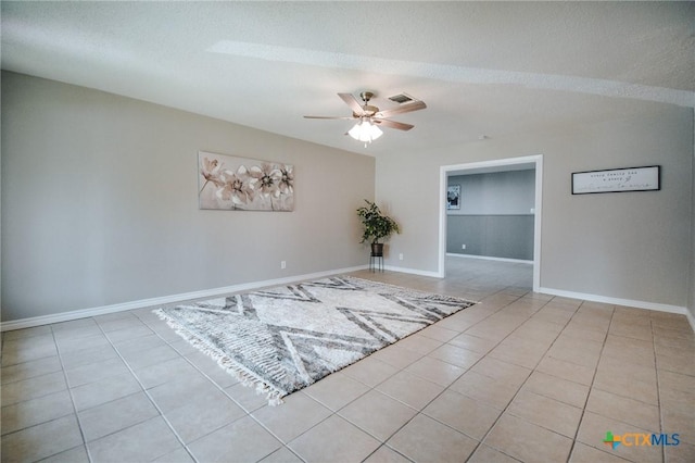 spare room featuring baseboards, a textured ceiling, a ceiling fan, and tile patterned flooring