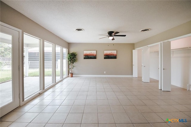 empty room with ceiling fan, visible vents, a textured ceiling, and light tile patterned flooring