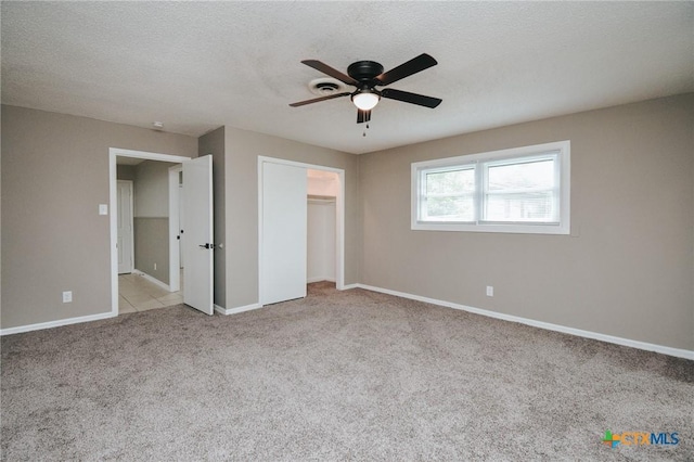 unfurnished bedroom featuring baseboards, ceiling fan, light colored carpet, a closet, and a textured ceiling