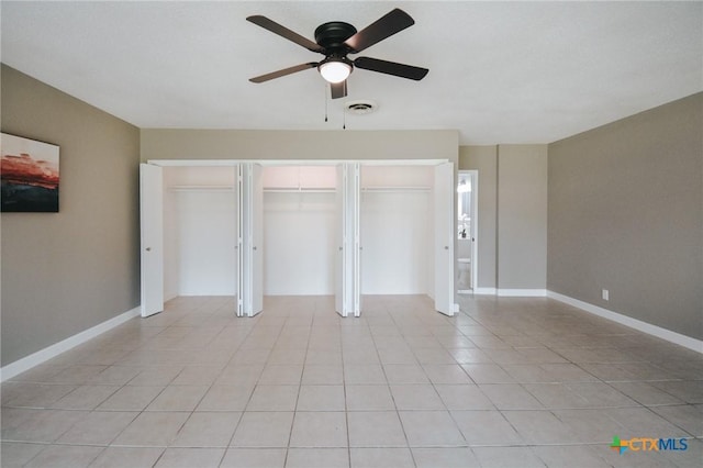 unfurnished bedroom with visible vents, a closet, light tile patterned flooring, baseboards, and ceiling fan