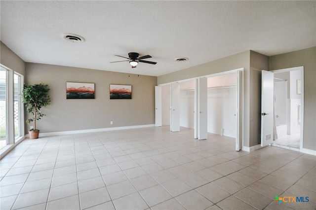 unfurnished bedroom with visible vents, baseboards, a textured ceiling, and light tile patterned flooring