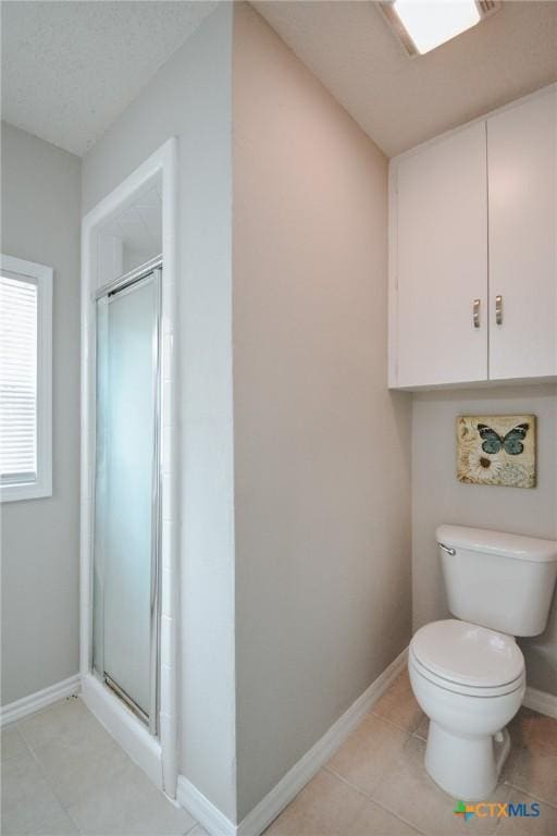 full bathroom featuring tile patterned flooring, a shower stall, toilet, and baseboards